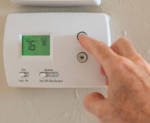 hand adjusting the temperature on the thermostat